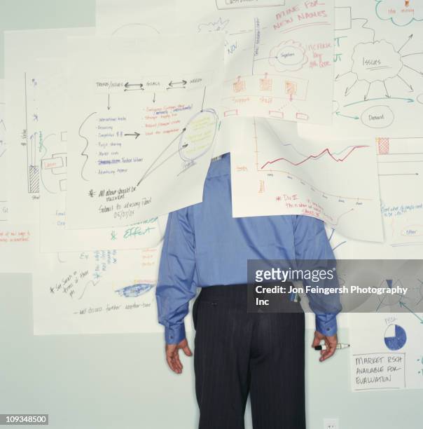 businessman hiding under drawings on office wall - hiding behind back stock pictures, royalty-free photos & images