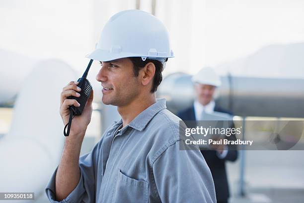 worker in hard-hat talking on walkie-talkie outdoors - walkie talkie stock pictures, royalty-free photos & images