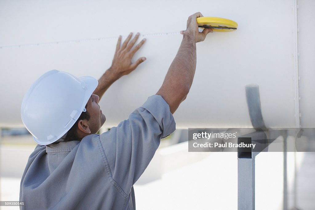 Worker measuring large pipe outdoors