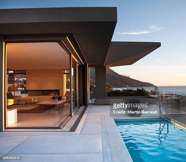 modern living room and patio next to swimming pool - huis interieur stockfoto's en -beelden
