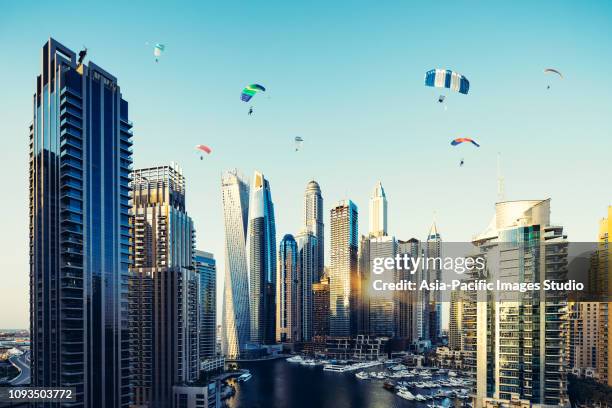dubai marina skyline and fun parachuting activities at dawn - skydiving stock pictures, royalty-free photos & images