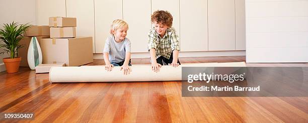 los niños de desenrollar alfombra nueva casa - carpet roll fotografías e imágenes de stock