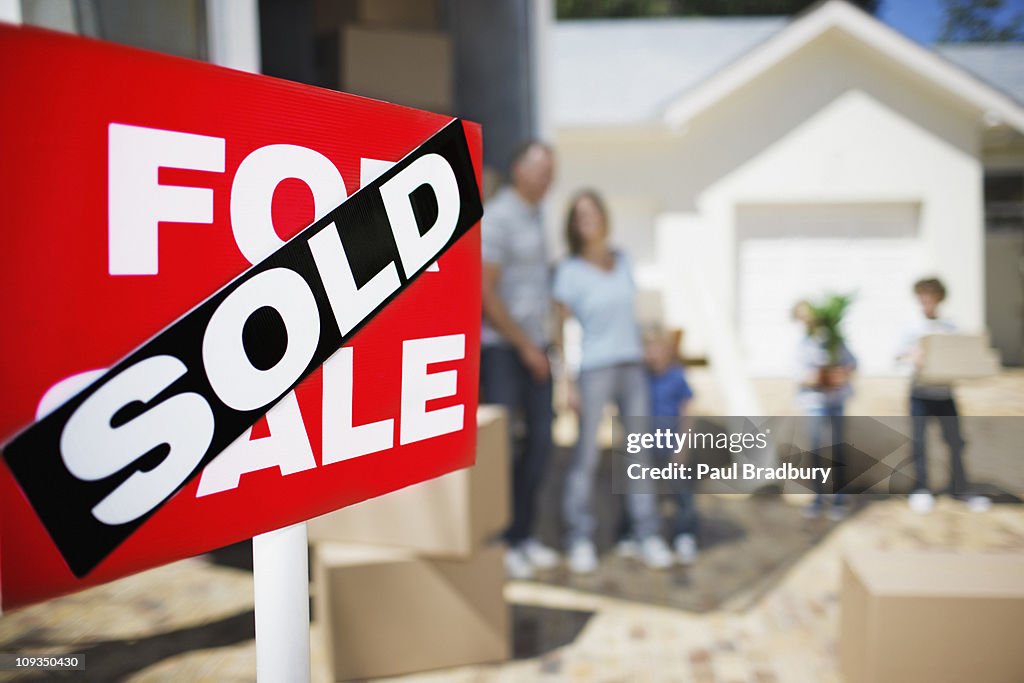 Sold sign on house with family in the background