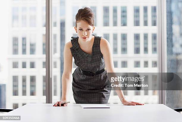 businesswoman leaning on desk in office - leaning stock pictures, royalty-free photos & images