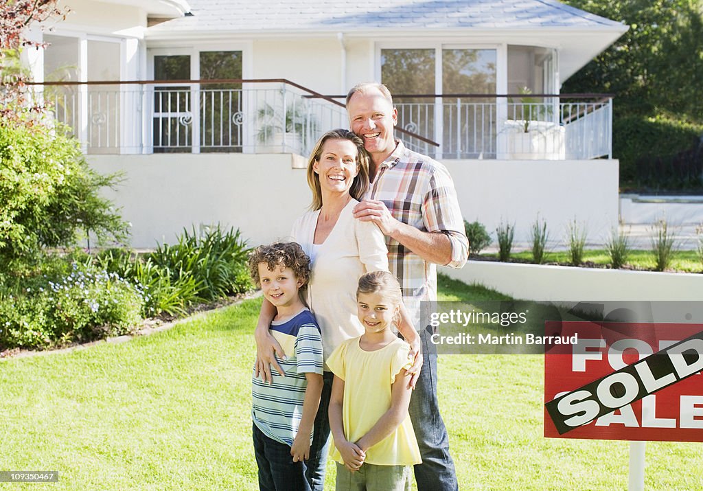 Famille debout dans le front yard de la nouvelle maison à côté