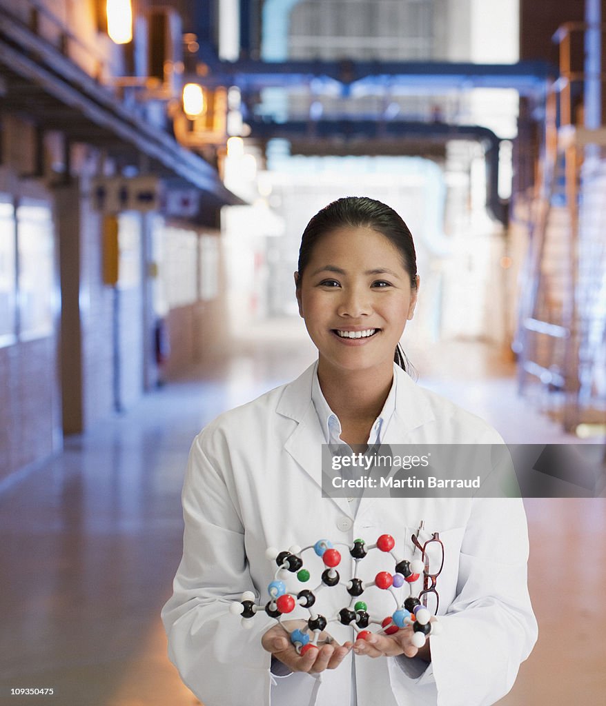 Scientist in factory holding molecule model