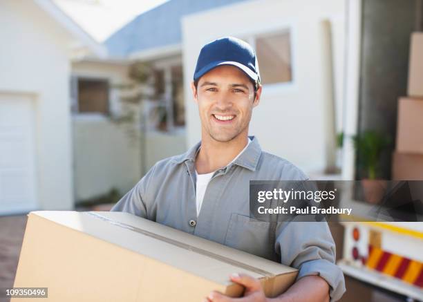 smiling man carrying box from moving van - carrying box stock pictures, royalty-free photos & images