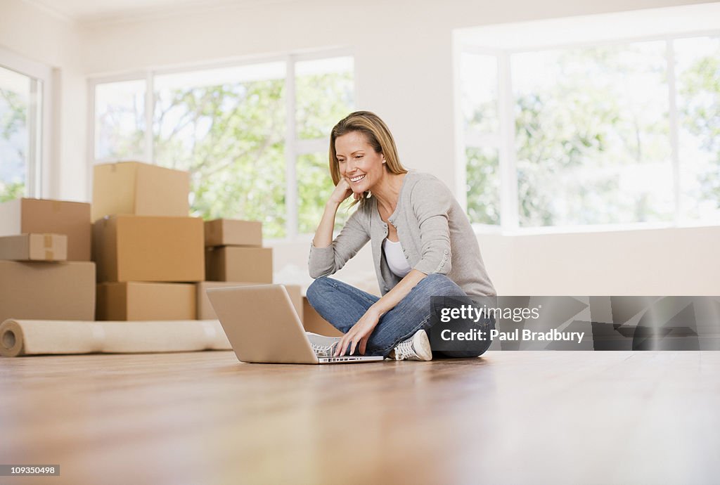 Woman using laptop on floor of her new house