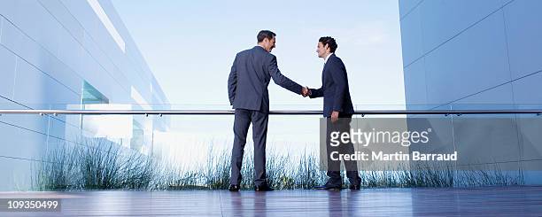businessmen shaking hands on balcony - business people handshake stockfoto's en -beelden