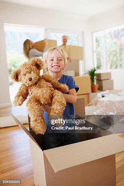 boy playing with teddy bear in box in new house - child picking up toys stock pictures, royalty-free photos & images