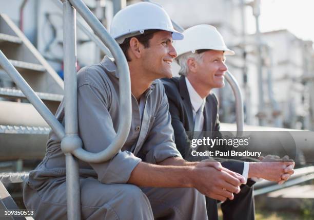 geschäftsmann und arbeiter in harten-hüte sitzen auf den industrial schritte - person in suit construction stock-fotos und bilder