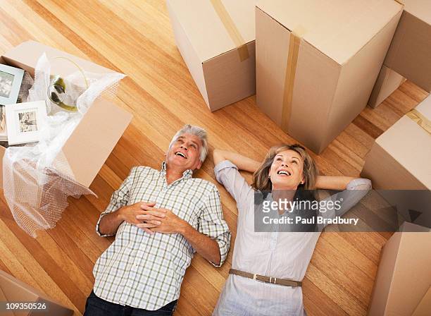 happy couple laying on floor of new house - baby boomer stock pictures, royalty-free photos & images