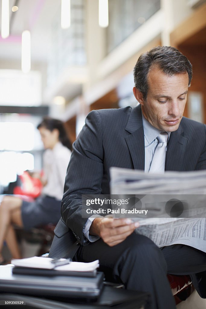 Businessman reading newspaper in hotel lobby