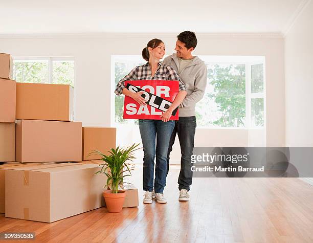 coppia holding venduto segno per la loro nuova casa - selling foto e immagini stock
