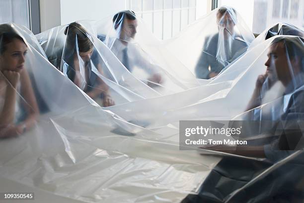 business people covered in plastic in conference room - tarpaulin stock-fotos und bilder