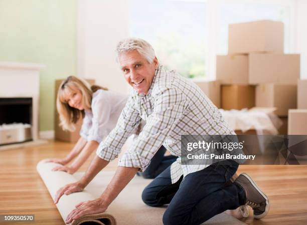 couple unrolling carpet in new house - new from rolls press stock pictures, royalty-free photos & images