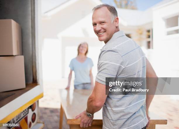 couple carrying table from moving van - turning back stock pictures, royalty-free photos & images