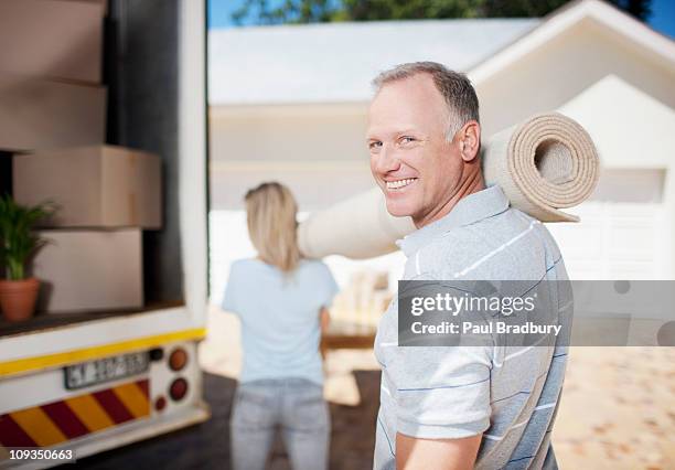 pareja de transporte de alfombra de las mudanzas - carpet roll fotografías e imágenes de stock