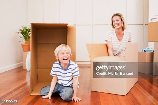 mother and son with boxes in new house - kneeling stock pictures, royalty-free photos & images