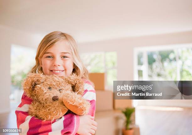 mädchen umarmen teddybär im haus - child teddy bear stock-fotos und bilder