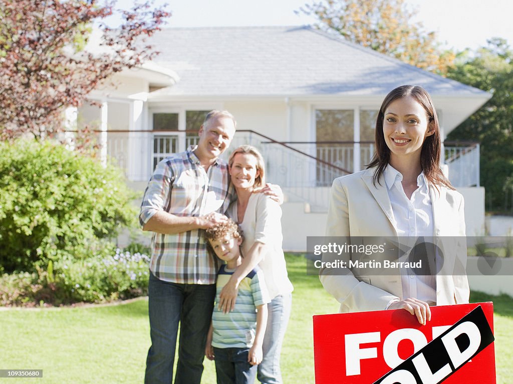 Real Estate Agent standing with family in front of new house