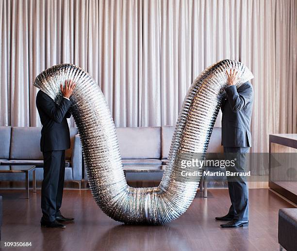 businessmen with their heads inside metal tubing - humor stockfoto's en -beelden
