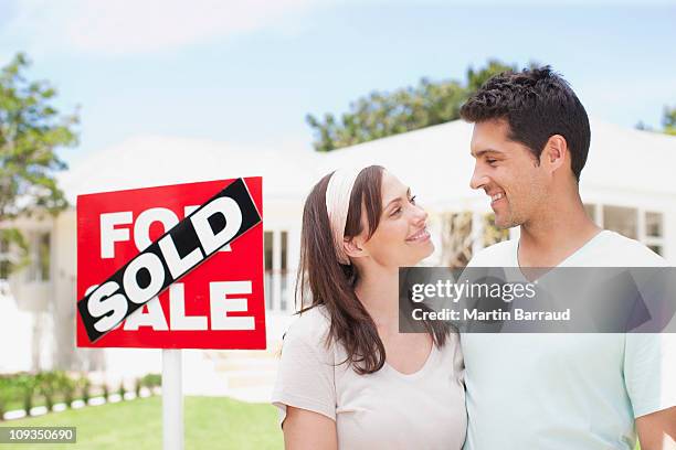 couple standing near sold sign of their new house - for sale sign stock pictures, royalty-free photos & images