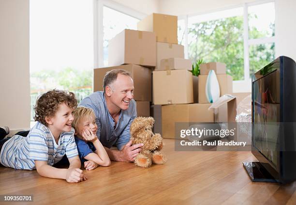 father and children watching television in new house - alter tv stock pictures, royalty-free photos & images