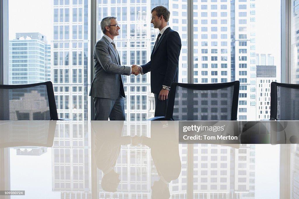 Businessmen shaking hands in conference room