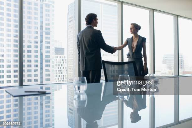 business people shaking hands in conference room - woman-man-handshake-across-table stock pictures, royalty-free photos & images