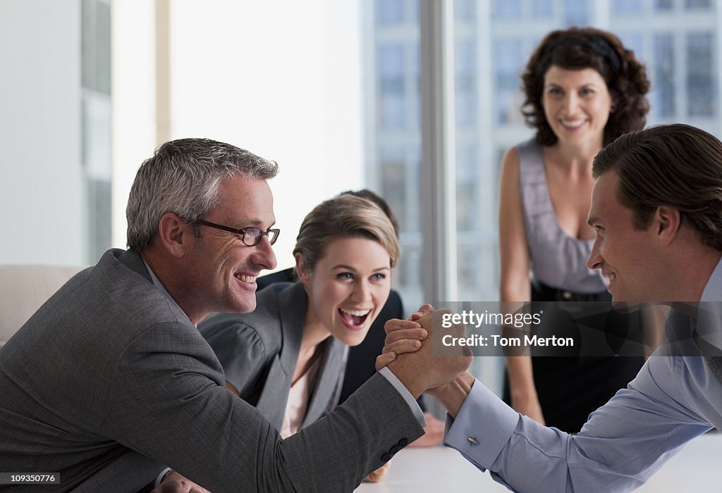 Business people watching businessman arm wrestling