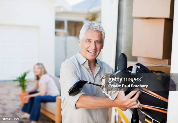 man removing golf clubs from moving van - senior golfer stock pictures, royalty-free photos & images