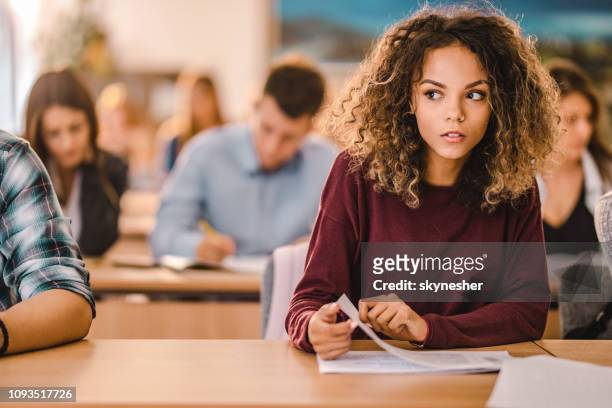 dishonest female student during a test in the classroom. - liar stock pictures, royalty-free photos & images