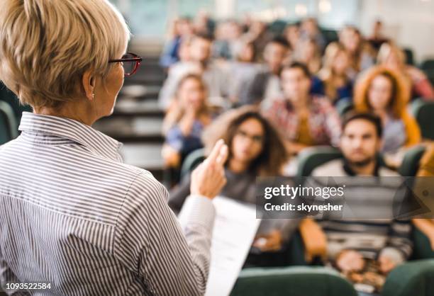 achteraanzicht van rijpe leraar geeft een lezing in een klaslokaal. - universiteit stockfoto's en -beelden
