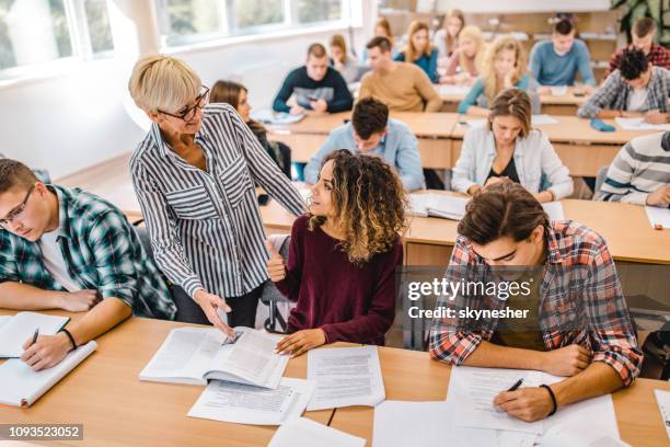 happy female college student talking to senior professor on a class in the classroom. - adult education stock pictures, royalty-free photos & images