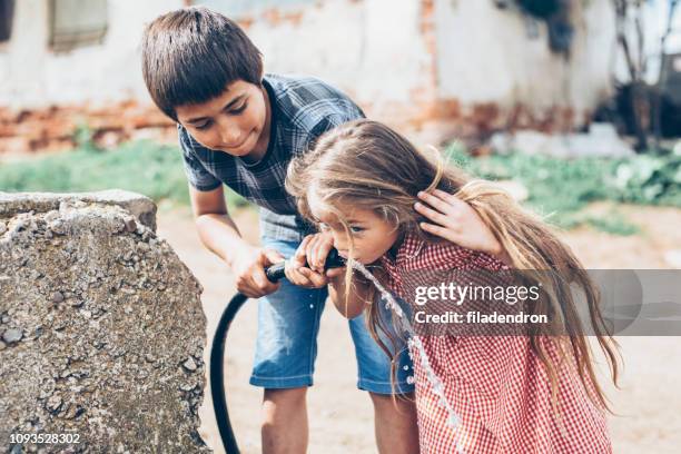 niños bebiendo agua de una manguera - niño-tomando-agua fotografías e imágenes de stock