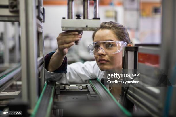ingegnere donna che esamina la parte della macchina su una linea di produzione. - women in stem foto e immagini stock