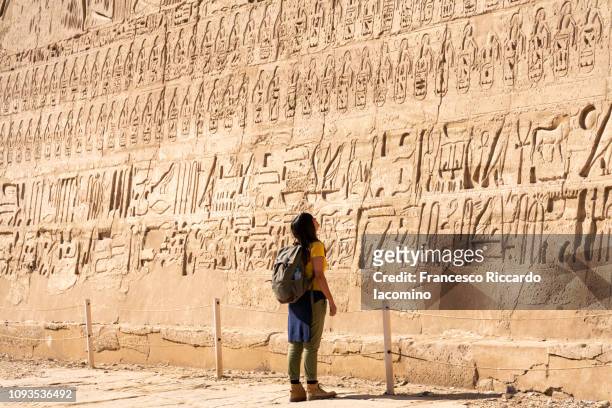 tourist girl admiring medinet habu temple, luxor - hieroglyphics stockfoto's en -beelden