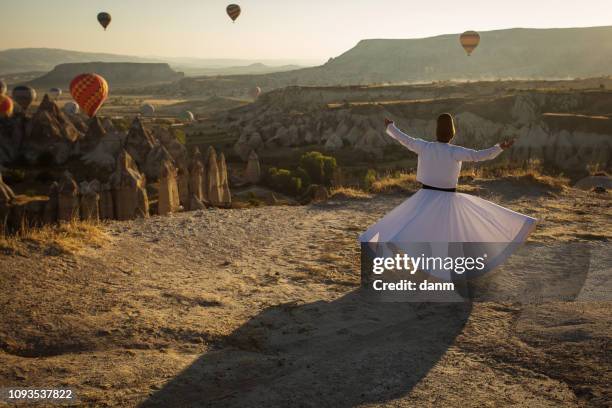 dervish doing the retual in love valley of cappadocia with balloons in background at sunrise. - sufismo imagens e fotografias de stock