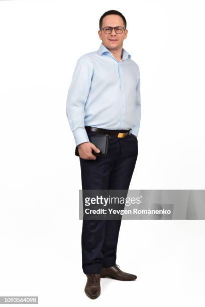 portrait of young prosperous businessman in spectacles dressed in formal shirt and trousers, holds black leather zip wallet in his hand. isolated on white background - formal shirt stock pictures, royalty-free photos & images