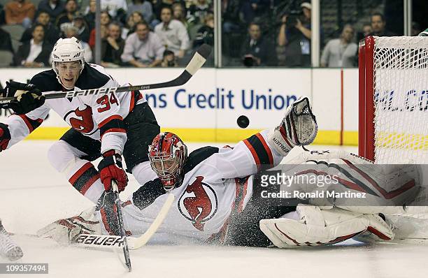 Goaltender Johan Hedberg of the New Jersey Devils makes a save against the Dallas Stars in front of Mark Fayne at American Airlines Center on...