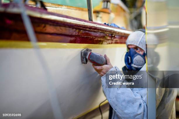 man using grinding machine, maintenance of sailing yacht in boathouse - repairing boat stock pictures, royalty-free photos & images