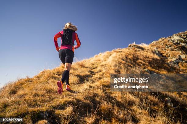 vista trasera cruz país mujer corriente arriba cordillera - empinado fotografías e imágenes de stock