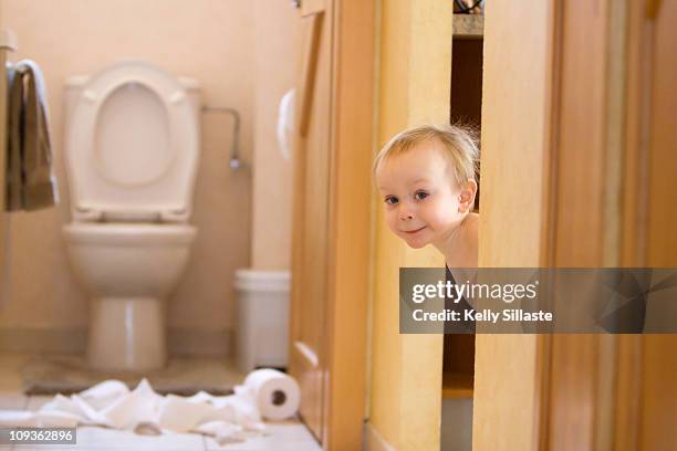 mischievous toddler boy playing with toliet paper - childrens closet stockfoto's en -beelden