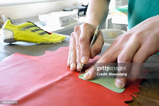 Trainee Patrick Schmerler cuts leather for a handmade soccer shoe at the Adidas AG factory in Scheinfeld, Germany, on Wednesday, Feb. 23, 2011....