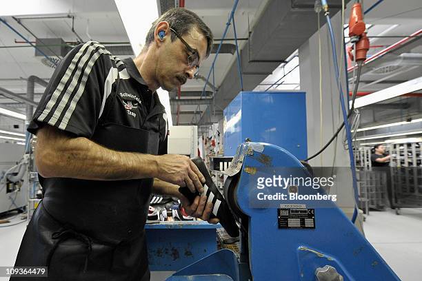 Employee Ingo Meixner removes the excess glue from a handmade leather soccer shoe at the Adidas AG factory in Scheinfeld, Germany, on Wednesday, Feb....
