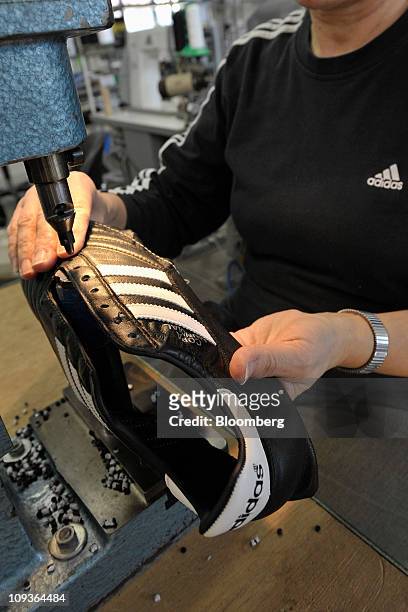 An employee cuts out the shoelace holes for a handmade leather soccer shoe at the Adidas AG factory in Scheinfeld, Germany, on Wednesday, Feb. 23,...