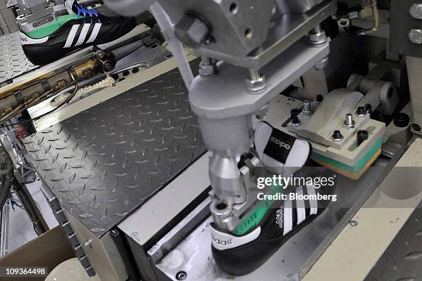 Machine attaches the plastic sole to a soccer shoe at the Adidas AG factory in Scheinfeld, Germany, on Wednesday, Feb. 23, 2011. Adidas AG has...