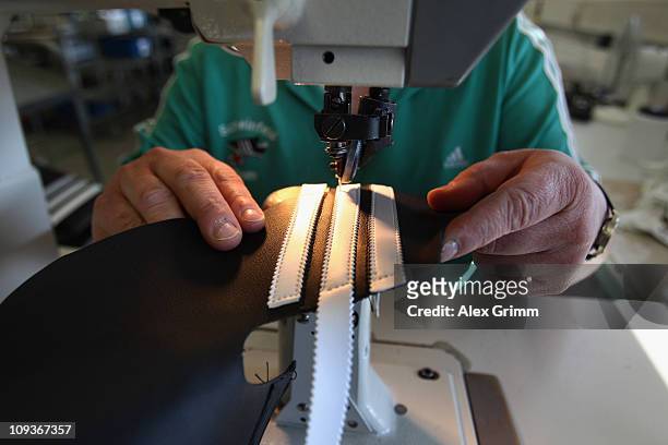 Employee Andrea Erbshaeuser stitches the three stripes on a football boot at the factory of German sporting-goods maker Adidas AG on February 23,...