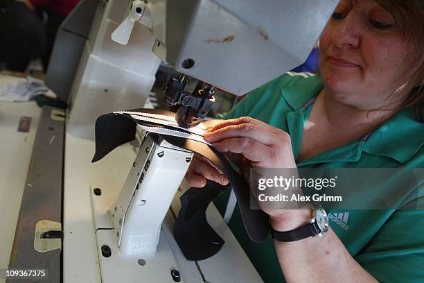 Employee Andrea Erbshaeuser stitches the three stripes on a football boot at the factory of German sporting-goods maker Adidas AG on February 23,...